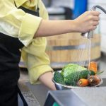 Preparation. Woman in the kitchen washing vegetables before cooking